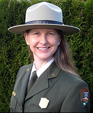 Close up of park ranger wearing felt ranger hat, green jacket, white shirt, and green tie.