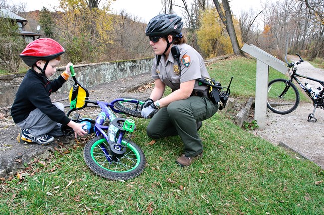 A ranger talks to a child with a bike.