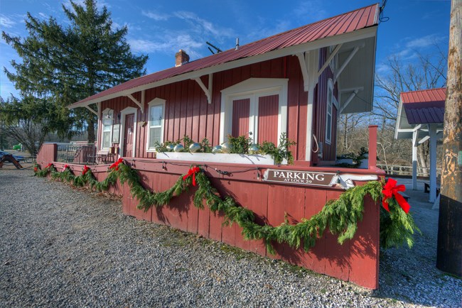 A red train depot decorated with garland and red bows.