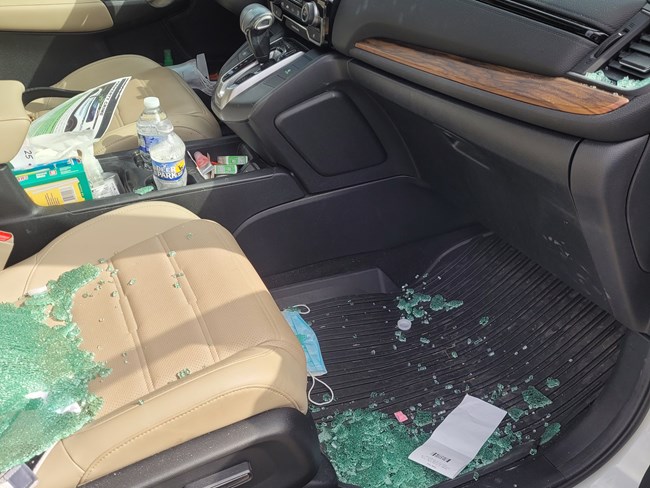 The inside of a car with glass smashed from the passenger window.