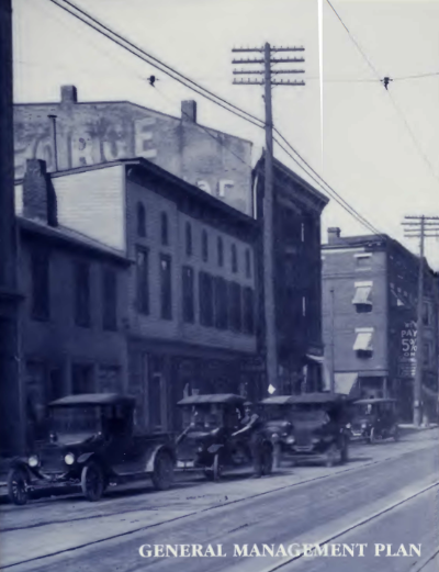 A row of brick buildings with cars parked in front of them along a street