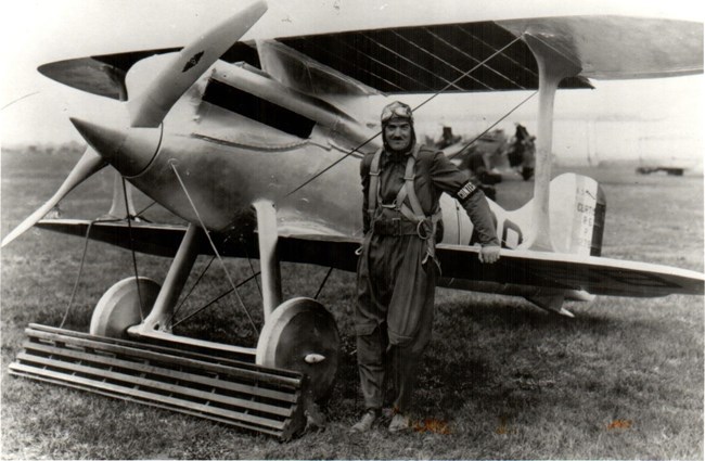 Captain Burt Skeel and his Army Curtiss R-8 Racer Black and white image of Captain Burt Skeel standing in front of his Army Curtiss R-8 Racer (airplane).