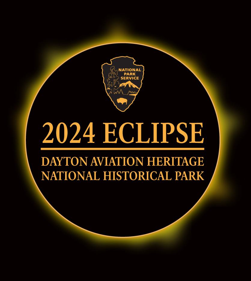 A yellow sun is fully eclipsed on a black background as the NPS arrowhead and park name hover in the center.