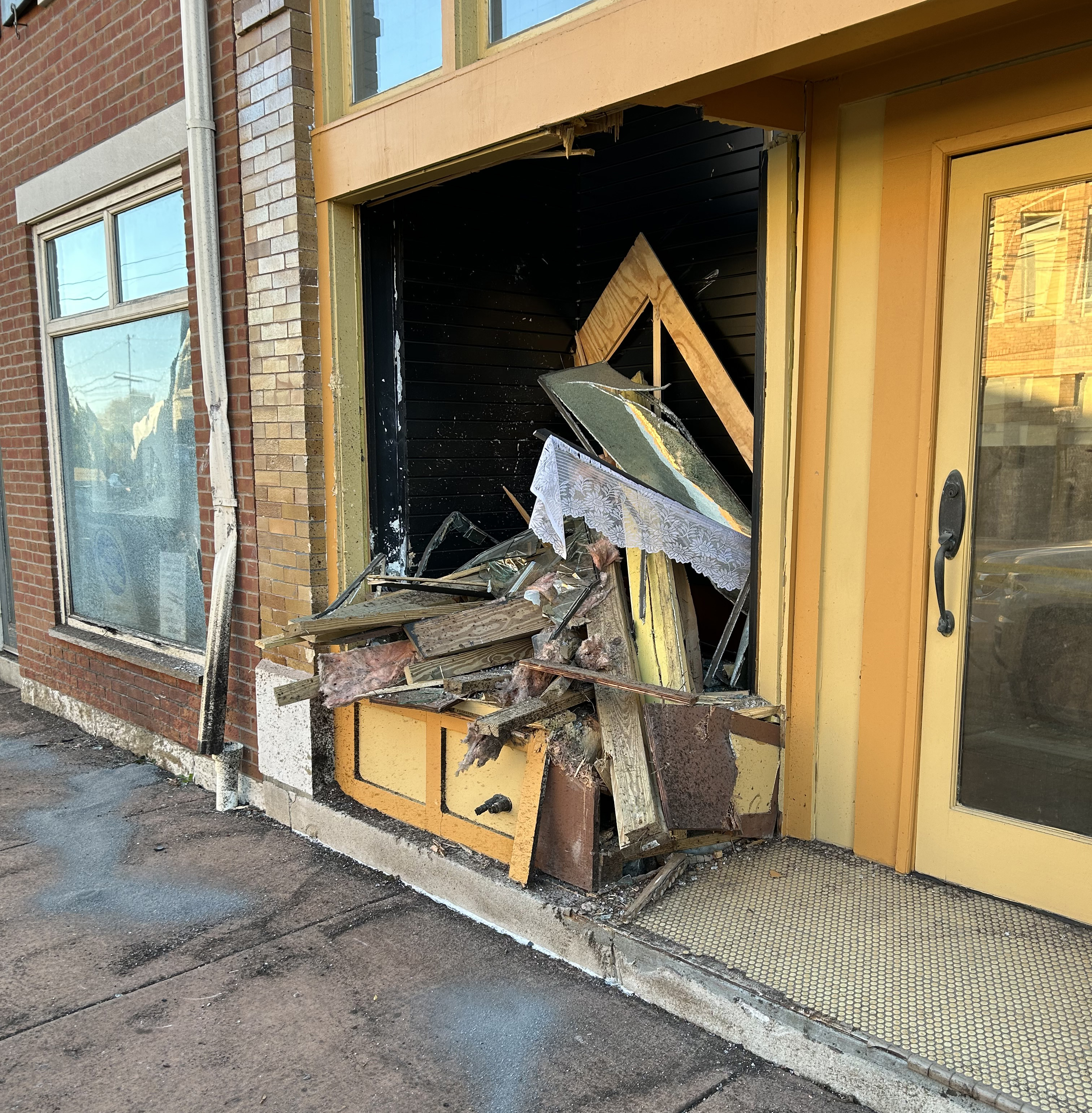 Peices of wood, metal and glass jut out of a damaged storefront.