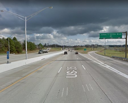 A green street sign above the highway