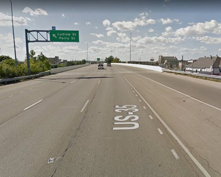 A green street sign above the highway