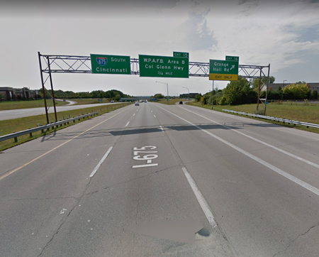 A cluster of green street signs above the highway