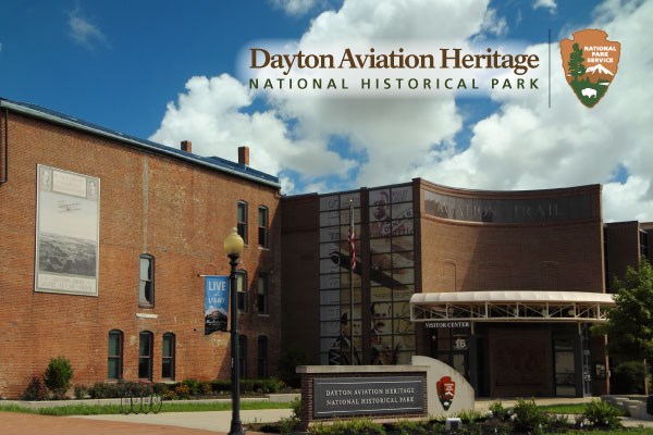 A large, three-story brick building with a lamppost and sign out in front of it.