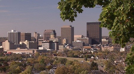 Several buildings in a city skyline with several trees in the foreground.