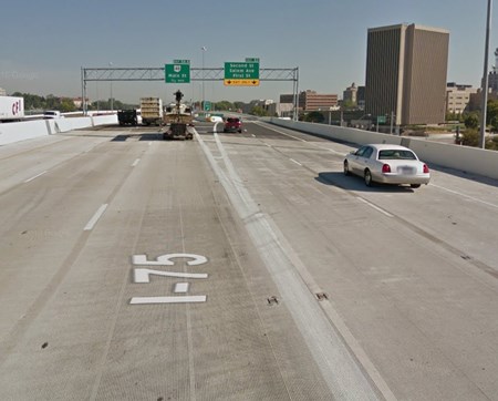 A green street sign above the highway