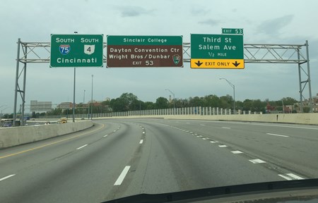 View of green, elevated road signs above a highway