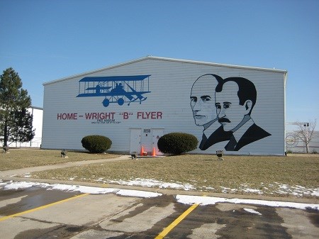 A large white building with the faces of two men on the right and an image of an old airplane on the left