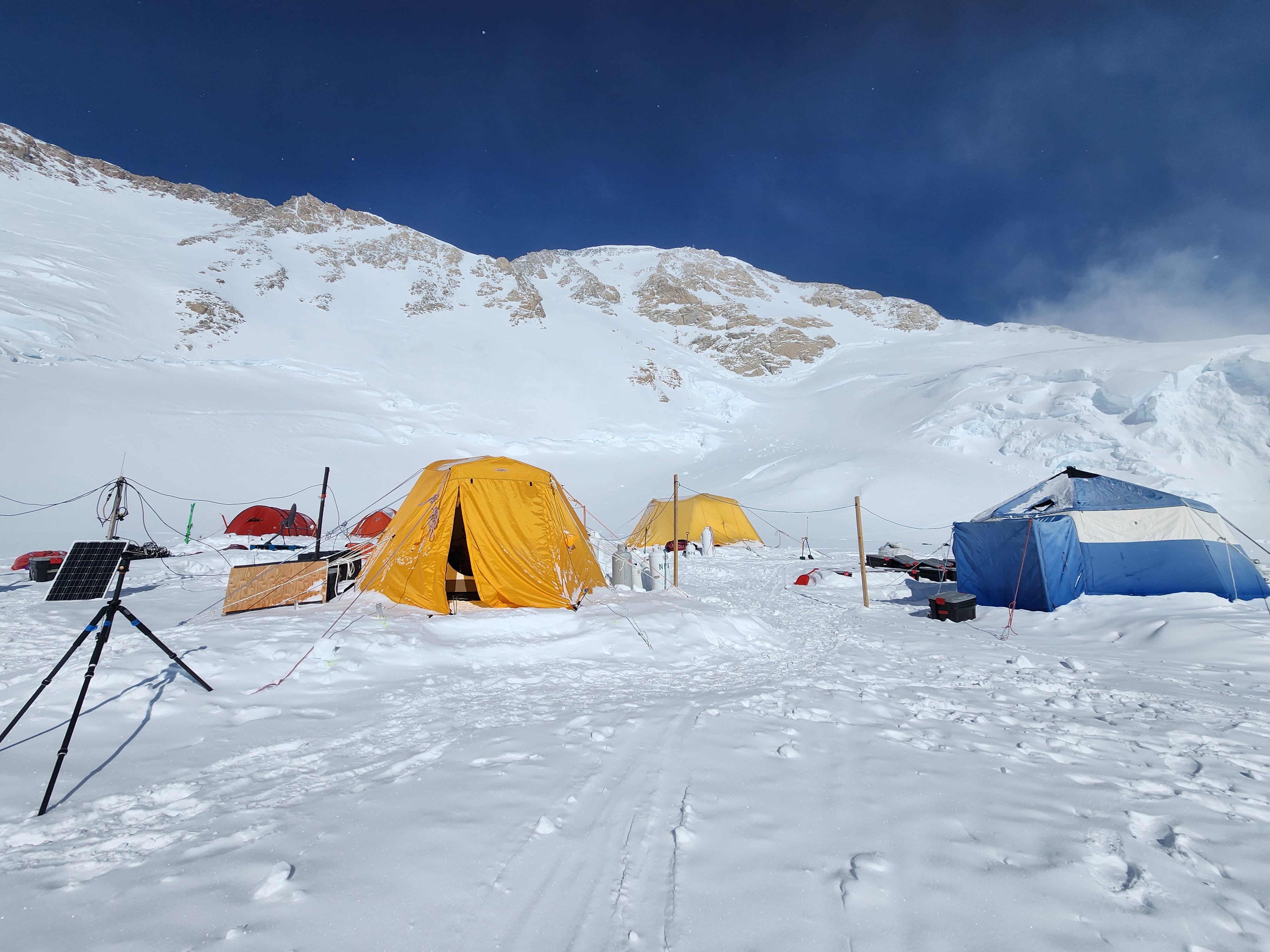 AFTER (NPS Photo / Jonah Olson) Glacier occupied by five large camp tents, several of which are connected to a solar panel with electrical wires.