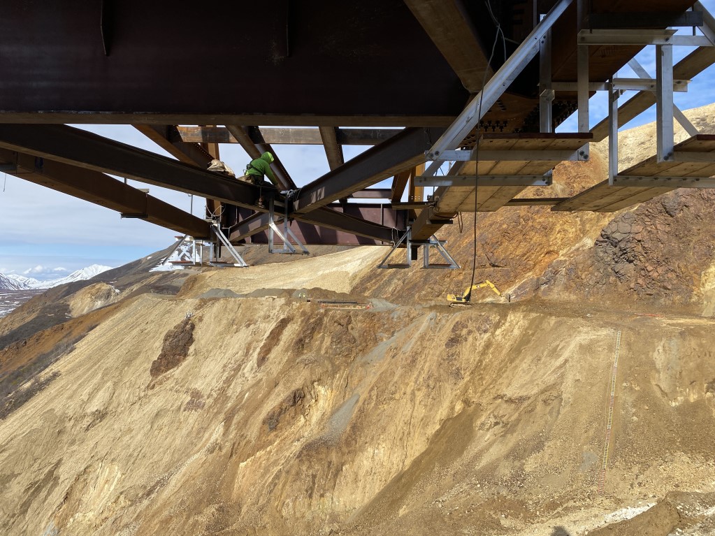 2025-05-23 bolting diagonals under L4-L3 FHWA Metal beams extend out over the landslide and a crew member works at the junction of two diagonal beams.