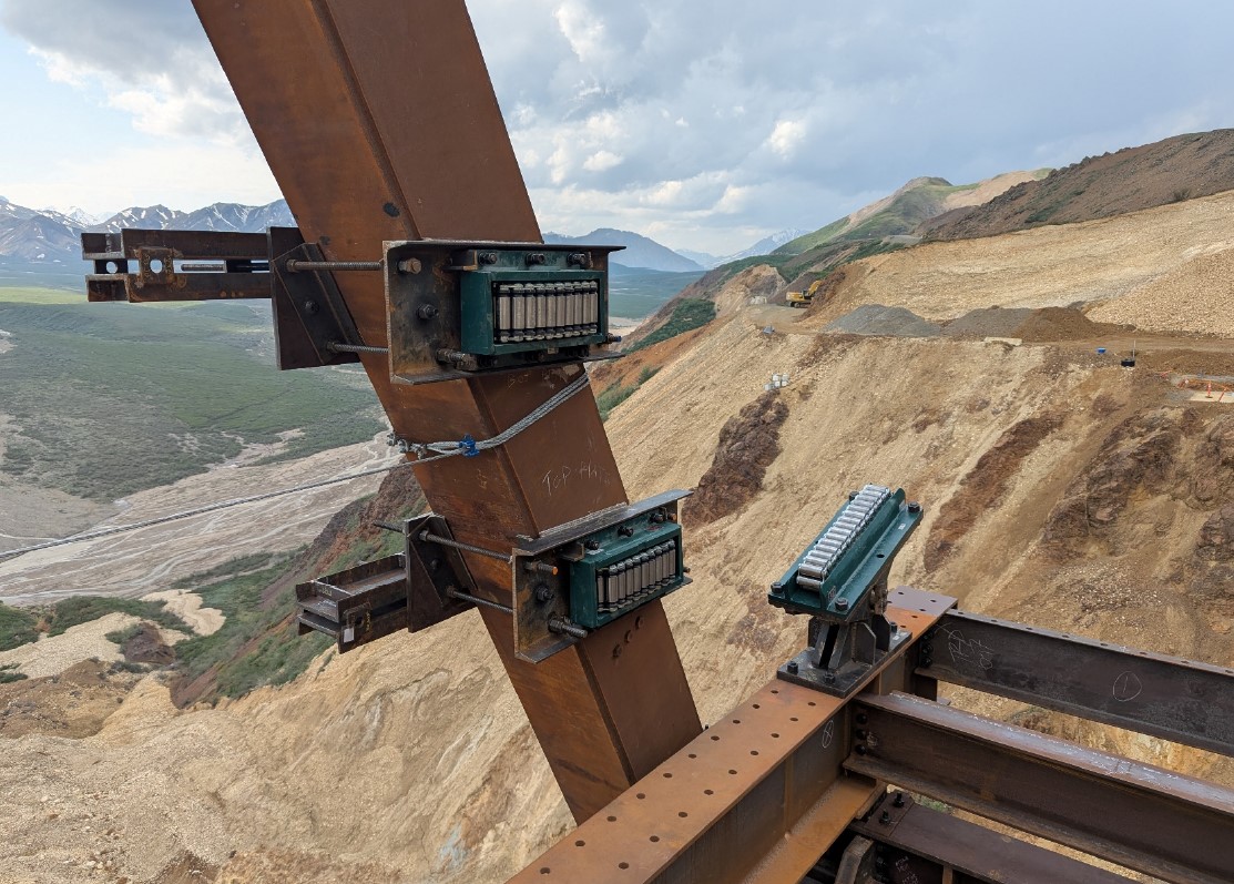 2025-06-20 lateral guide rollers Jacobs Three rollers attached to metal beams. The mountainside and river valley can be seen far below the metal beams.