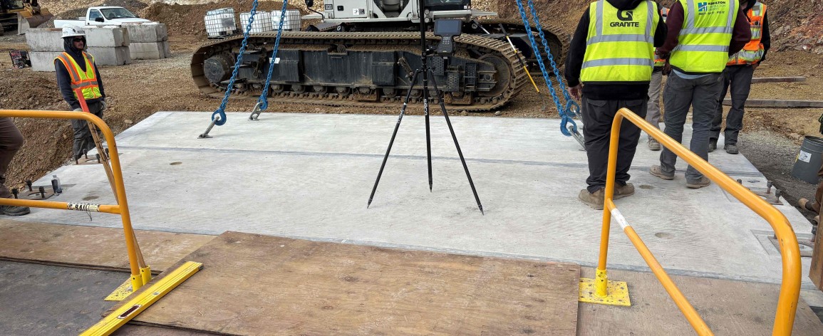 A flat slab of concrete surrounded by equipment and several construction workers.