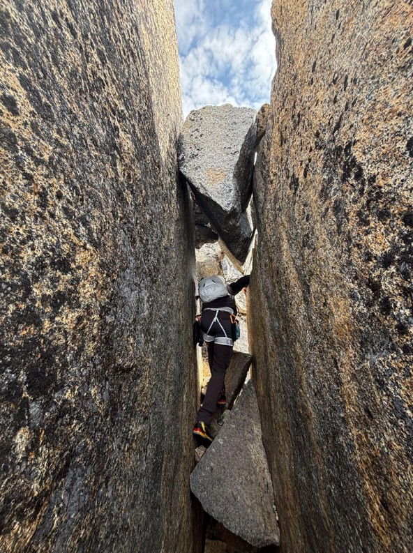 A chockstone chimney variation A ranger climbs through a rocky crevasse