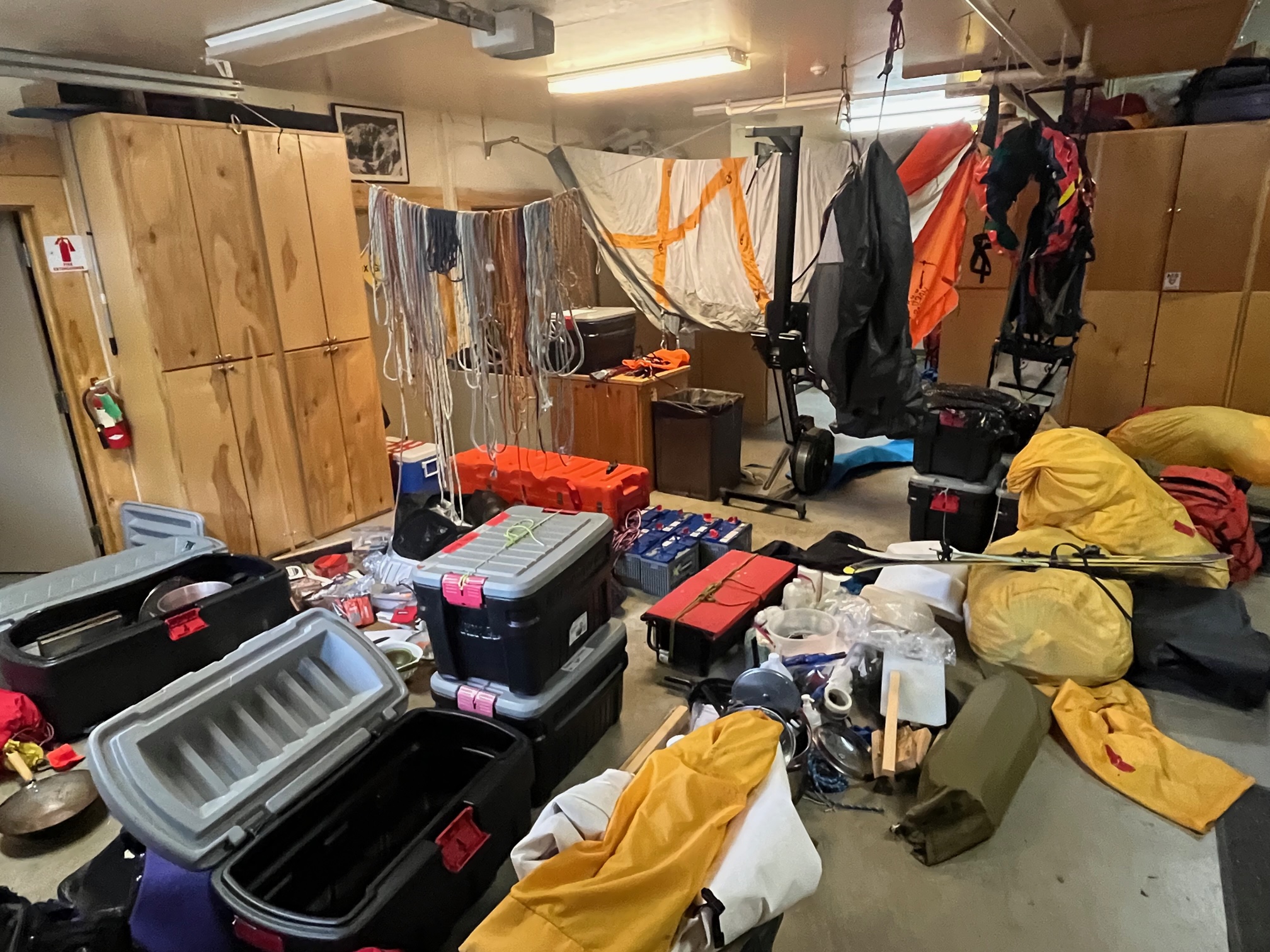 A garage filled with hanging tents, ropes, piles of assorted climbing gear and storage totes.
