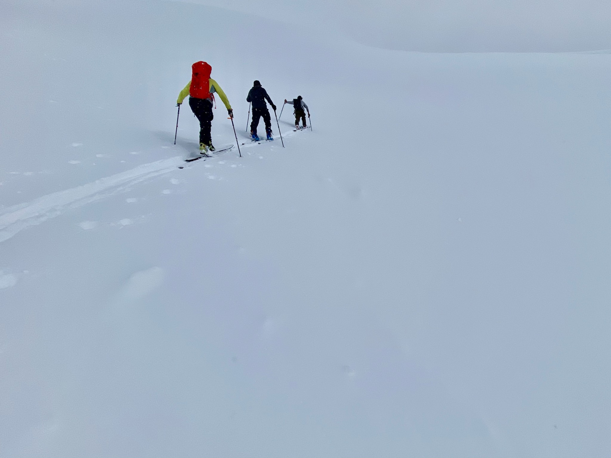Below the Messner Three skiers skin uphill