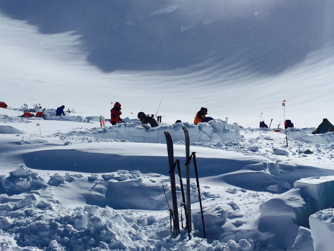 Snowy, windswept camp with bundled up climbers Snowy, windswept camp with bundled up climbers