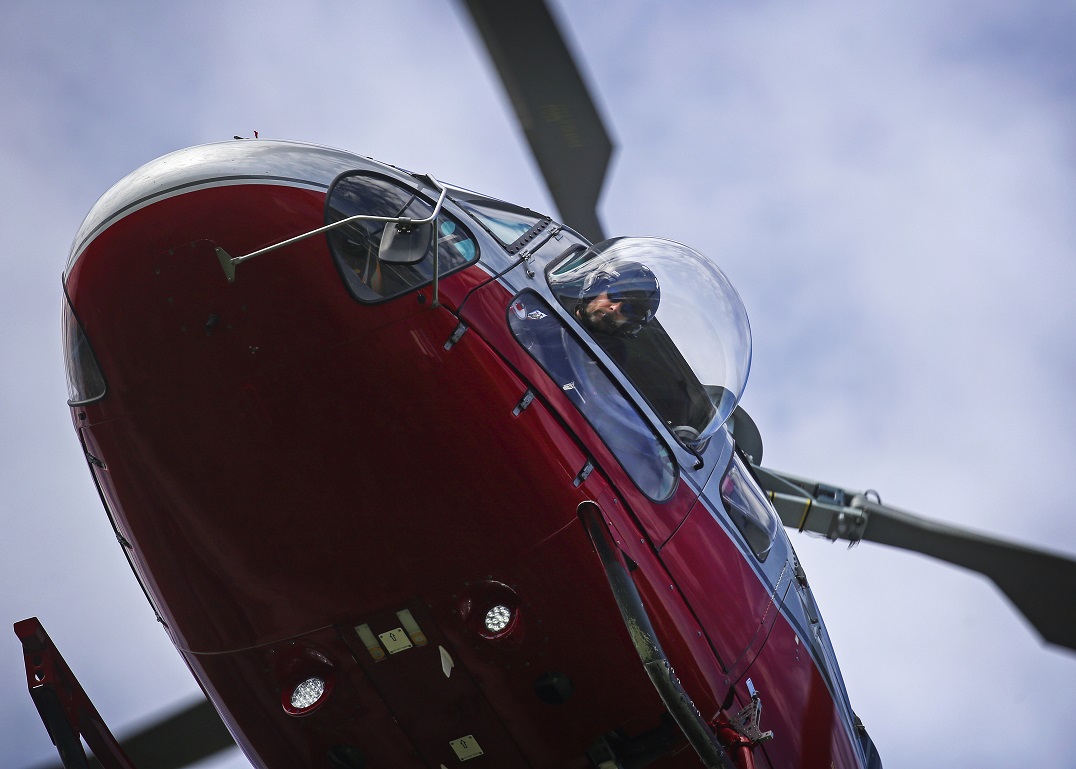 Helicopter pilot peers out of his bubble window at the terrain below 