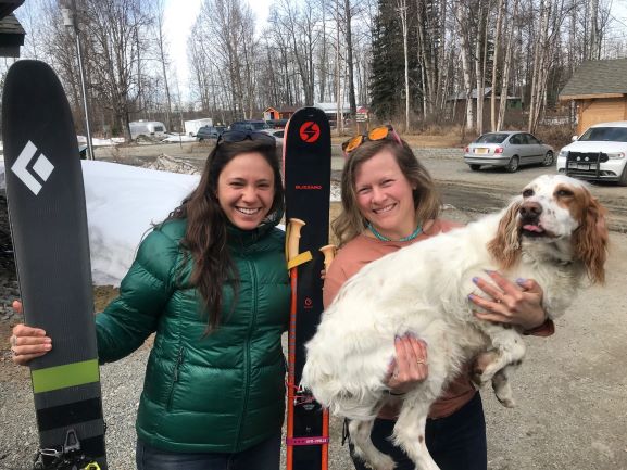 Sam, Chrissie, and Odysseus-the-Wanderer Two women with skis, one with an adorable dog in her arms