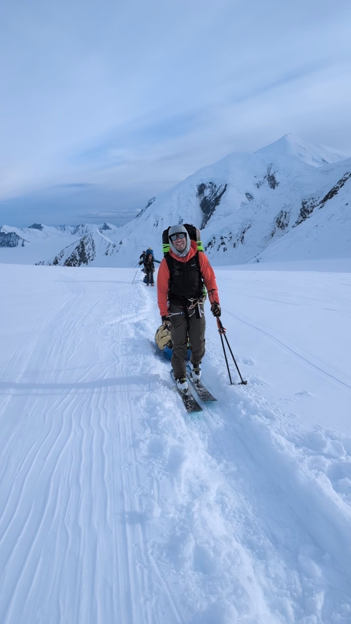 Clean up Patrol 4 Two rangers skiing toward the camera. The ranger in front is smiling and wearing an orange jacket and black snow pants.