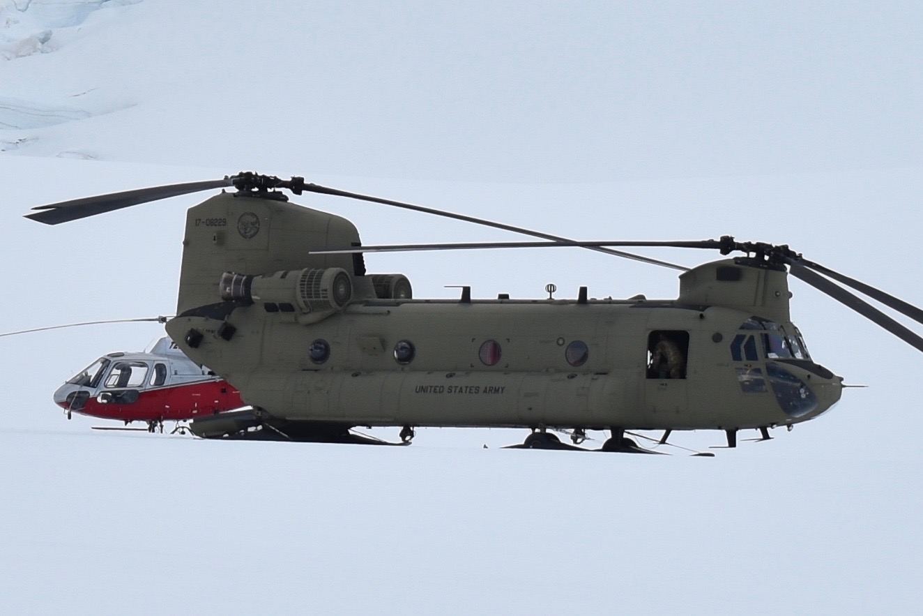 Two hellicopters, one big one small, on a glacier