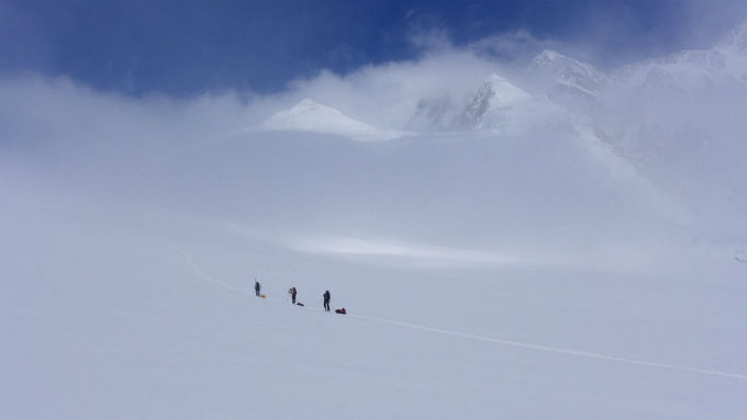 A rope team of three climbers travels across a glacier