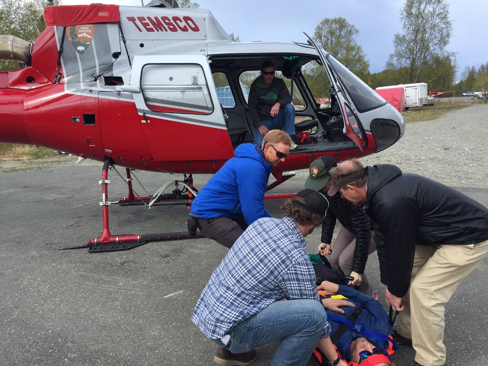 Patrol members lift a backboarded patient into a helicopter 