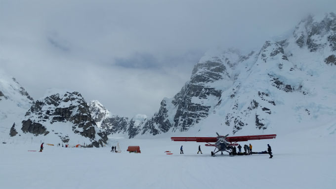 An image of a small airplane on a glacier surrounded by climbers