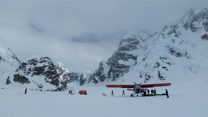 An image of a small airplane on a glacier surrounded by climbers An image of a small airplane on a glacier surrounded by climbers