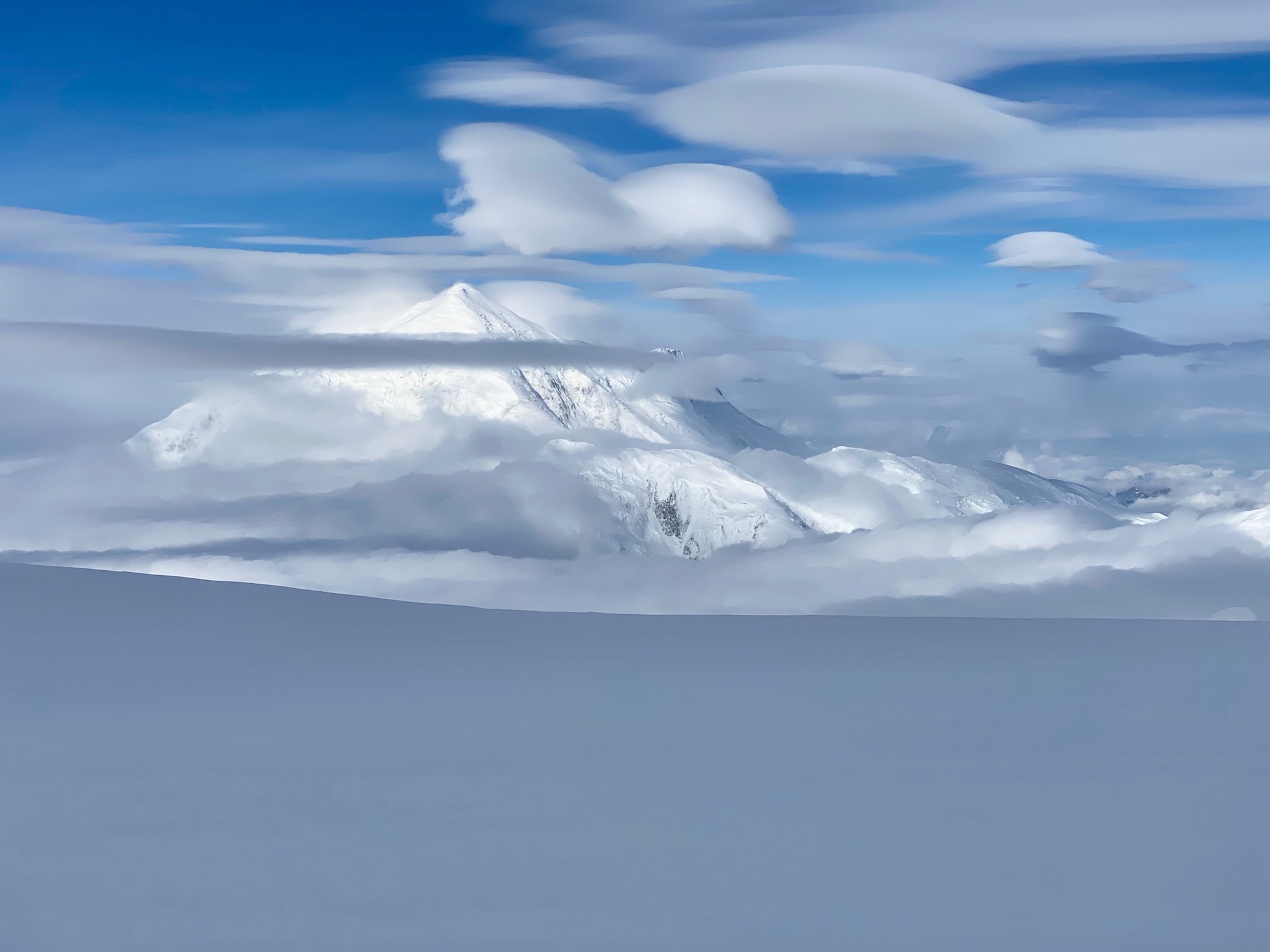Mountain peak as seen through layers of lenticular clouds