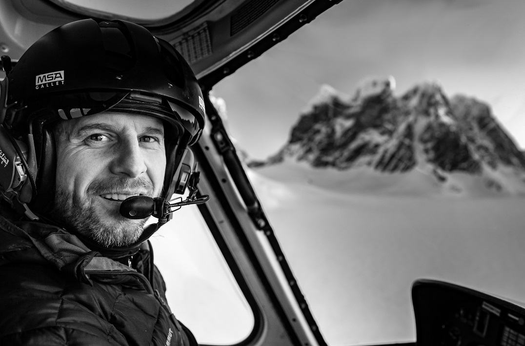 A helicopter pilot flying in snowy, mountainous terrain