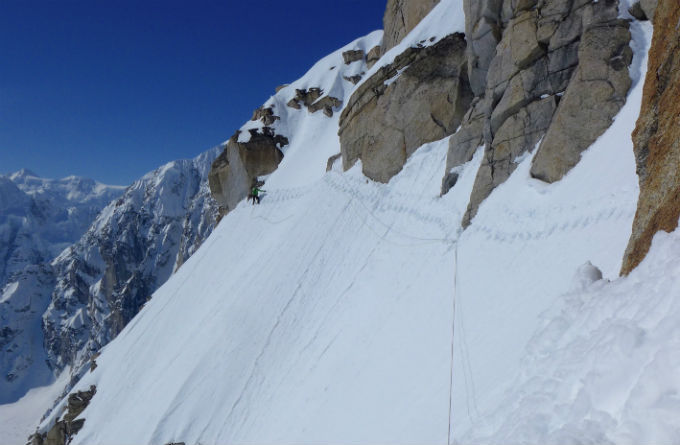 Mountain face with tracks traversing a near-vertical snow field