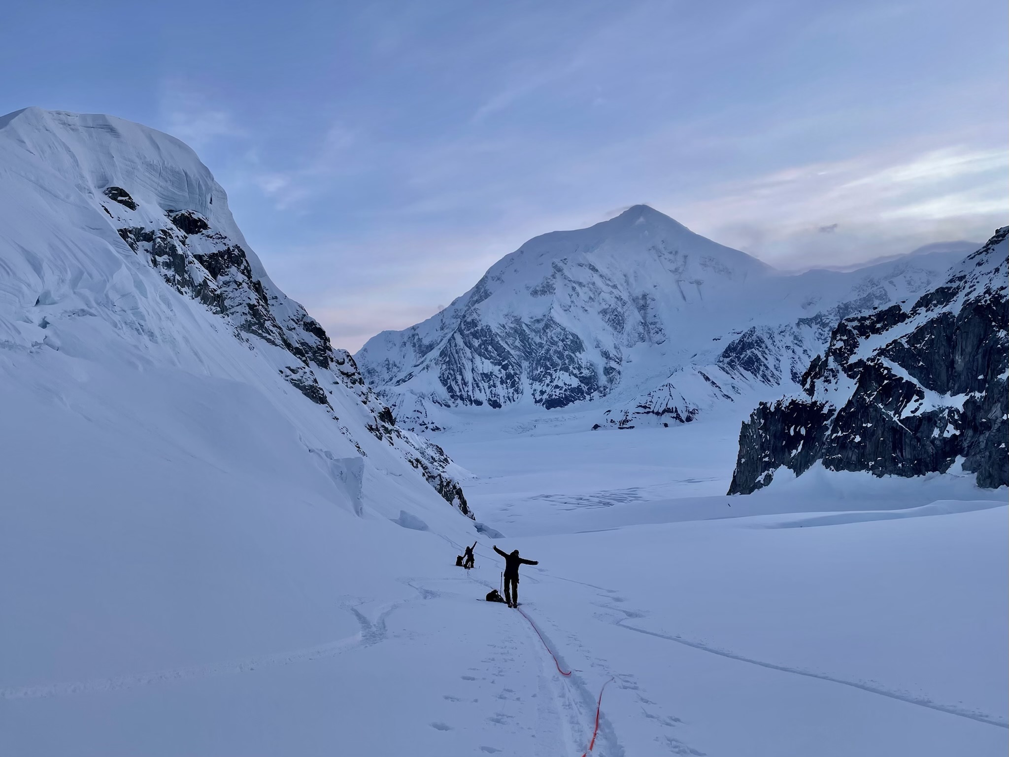 Two climbers take a stretch break en route to a snowy ridge