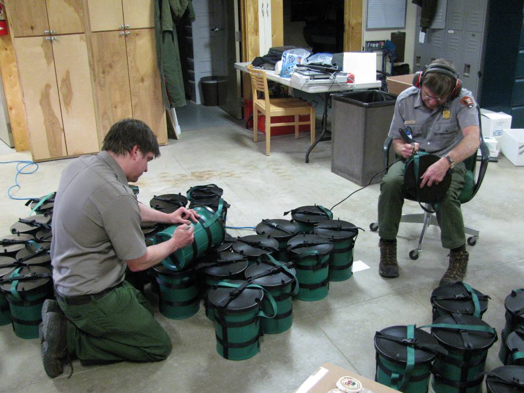 Two rangers engrave numbers on a stack of new CMCs