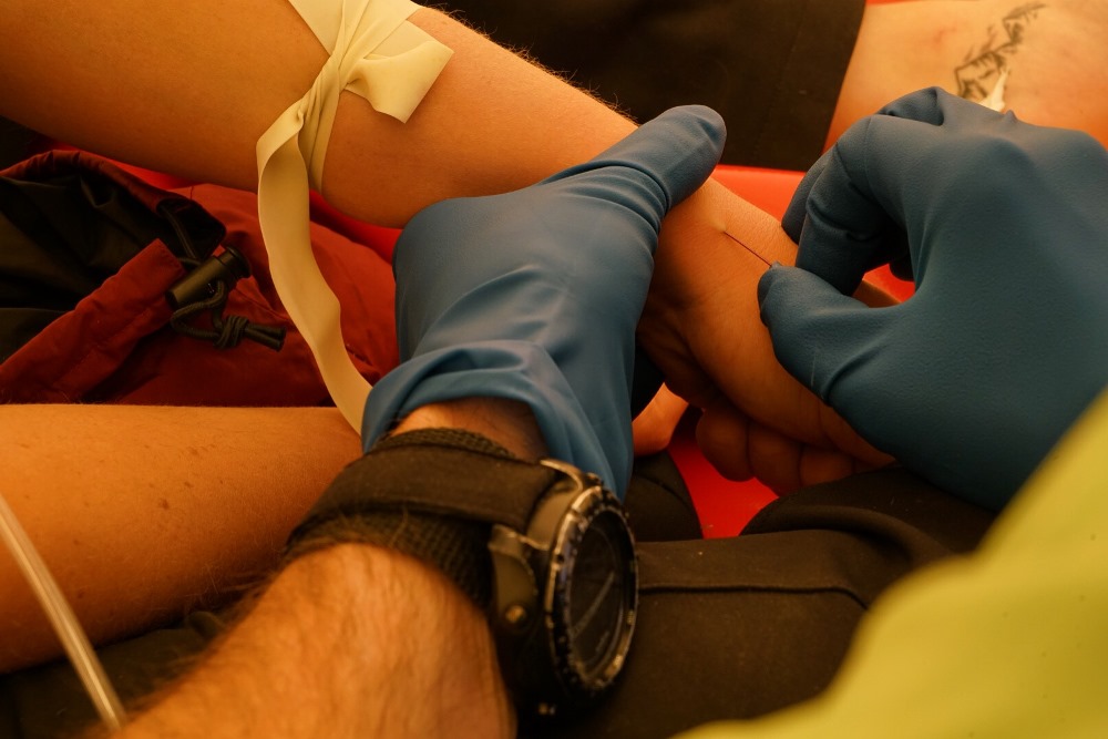 Ranger/medic places an IV in a patient's arm