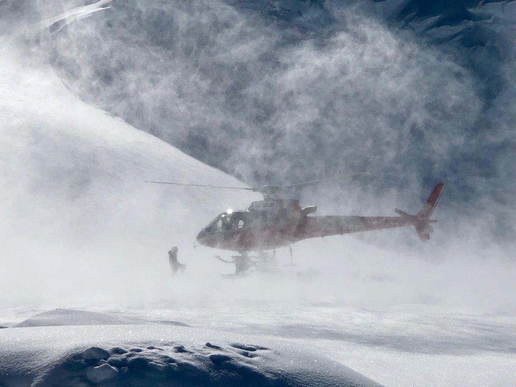 Helicopter sets down on the glacier kicking up a mist of snow