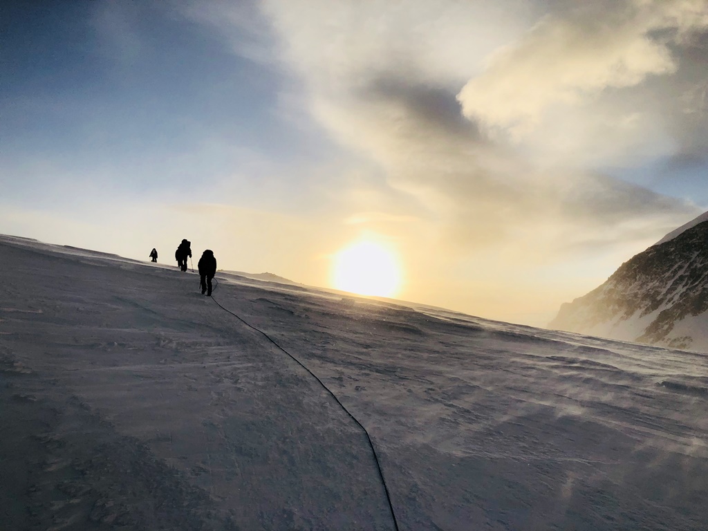 Into the Sunset A rope team climbs a snowy ridge during sunset