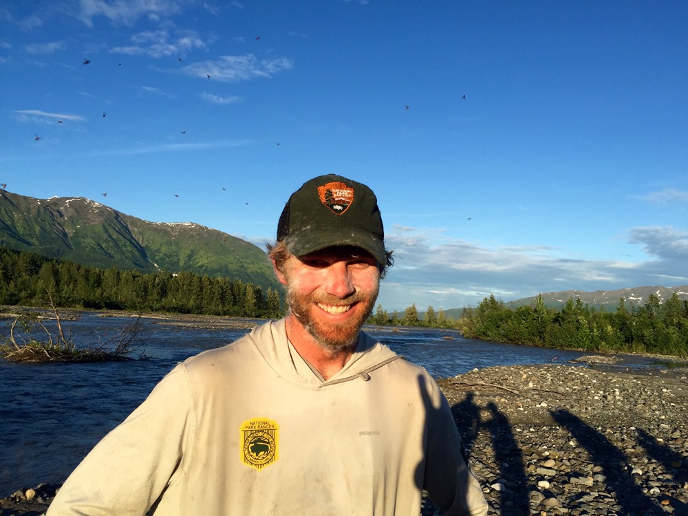 Done with bushwhacking, Chris makes it out to the river in a cloud of mosquitoes 