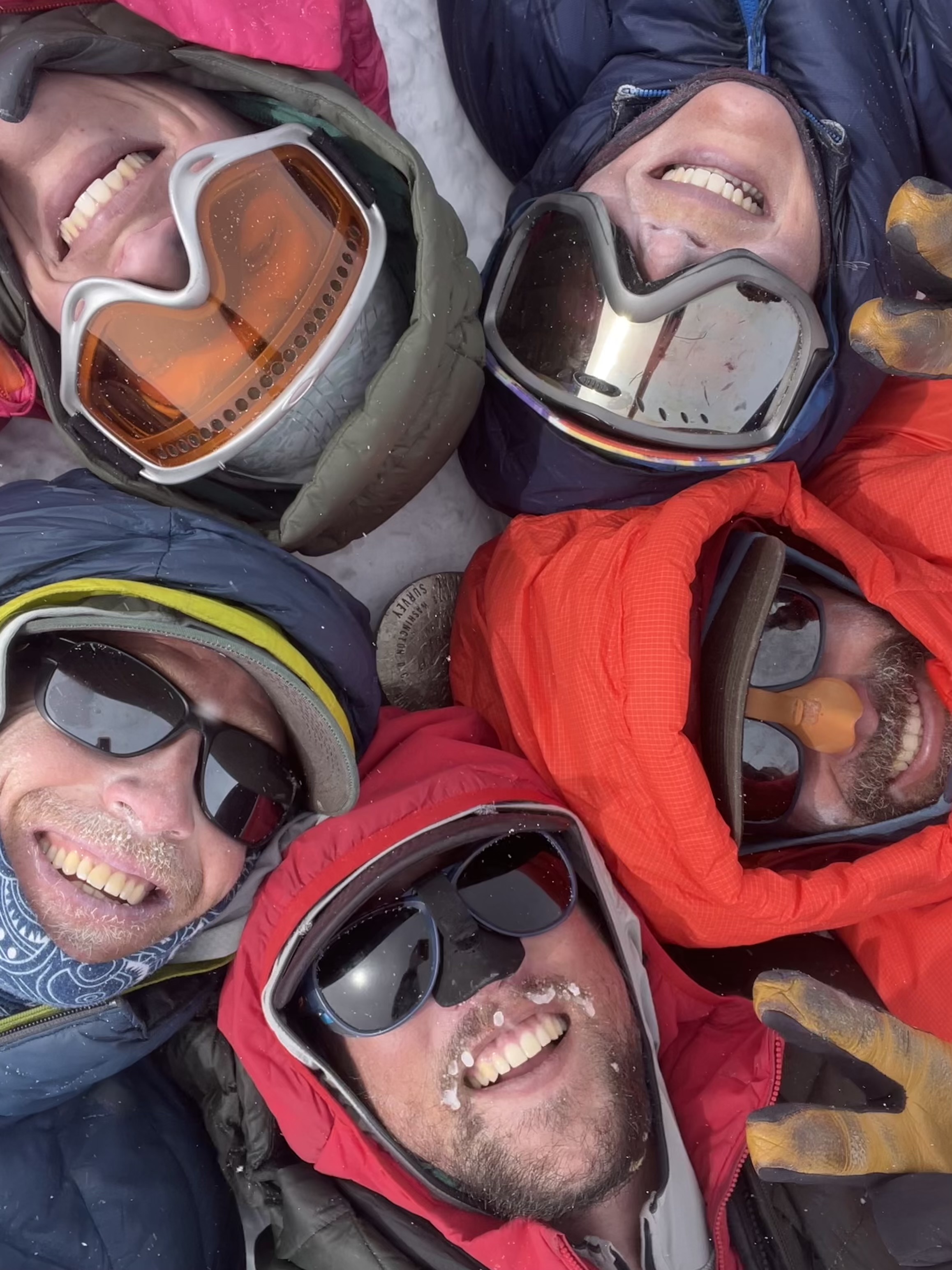 Summit Shot Closeup View from above of five hooded, smiling faces in a circle