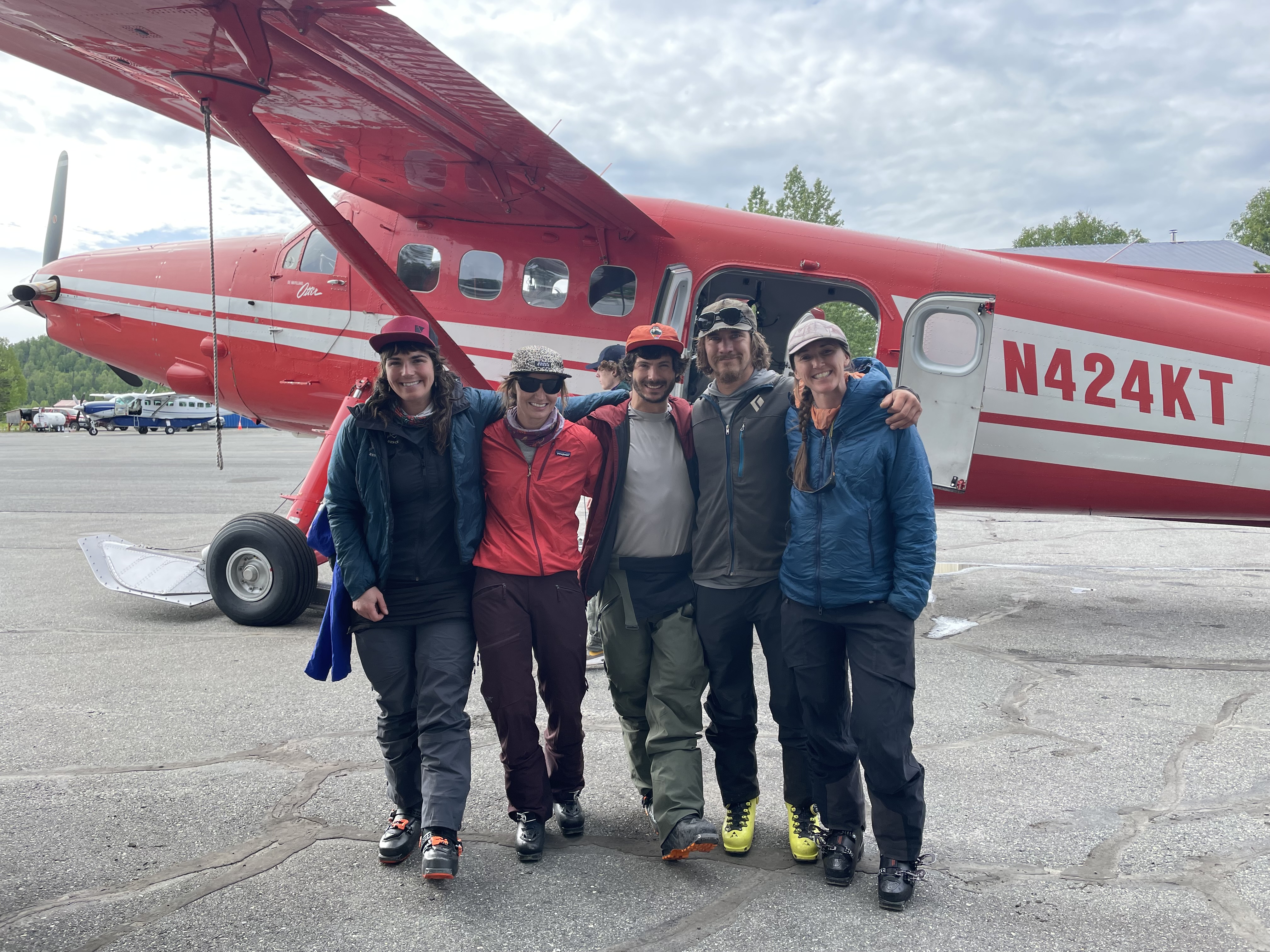 Cleanup crew 2023 Five climbers link arms in front of a small red aircraft.
