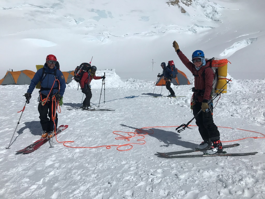 Four mountaineers with heavy packs at 14,200 foot camp