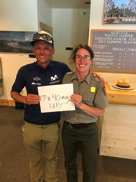 A ranger poses with a climber holding a placard saying 7 H 40 Mins UP! 