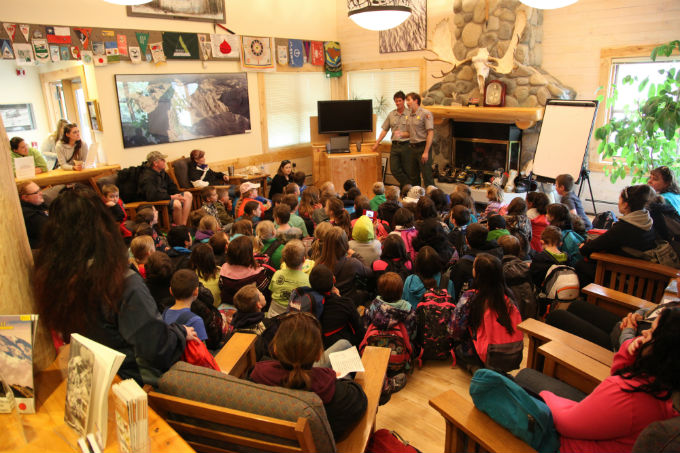 Two rangers address a room full of kids at the Ranger Station.