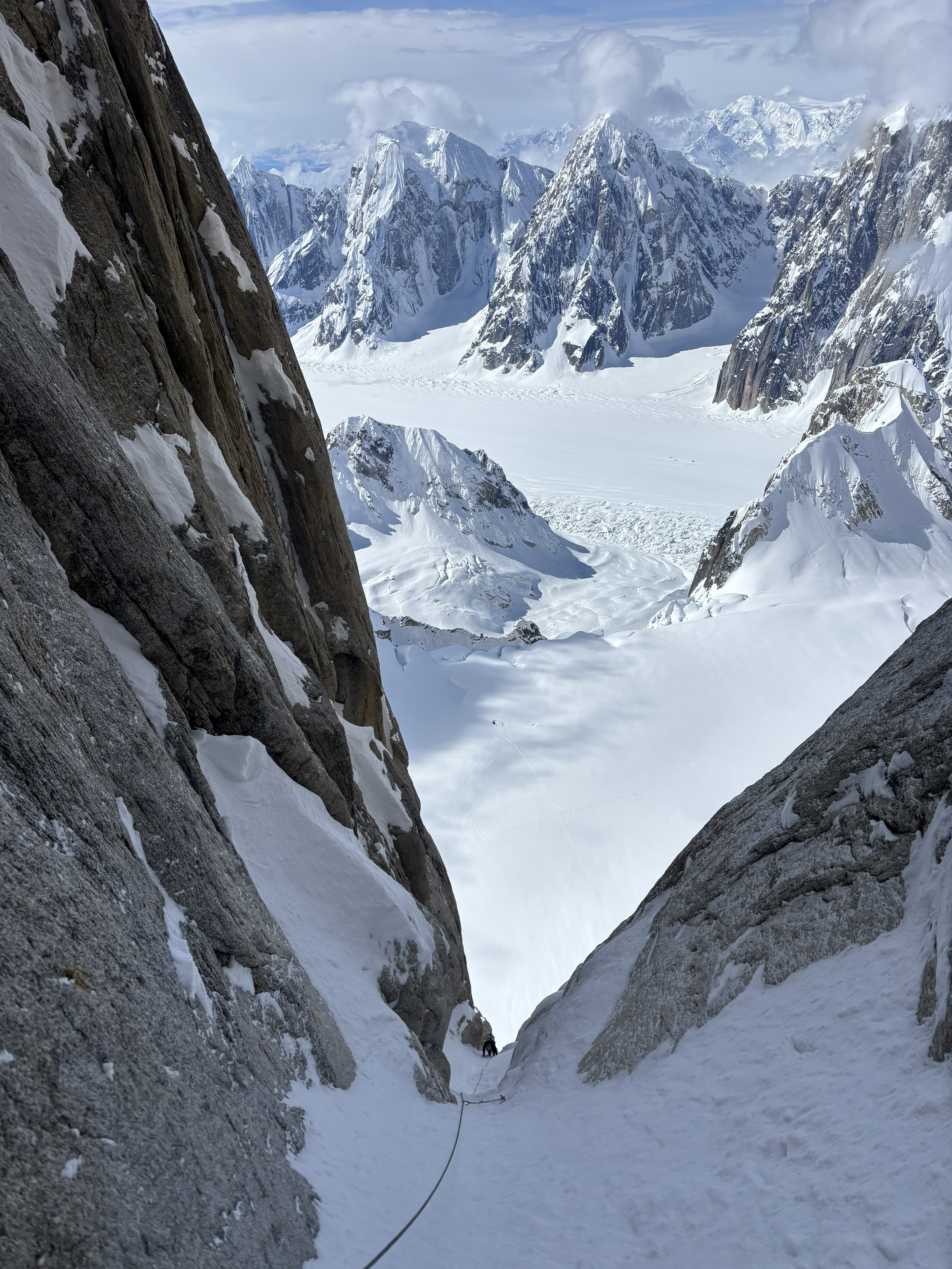 Looking down the choke from the top of the 9th pitch A rope lays on a snowy rock pitch over looking snow covered mountains