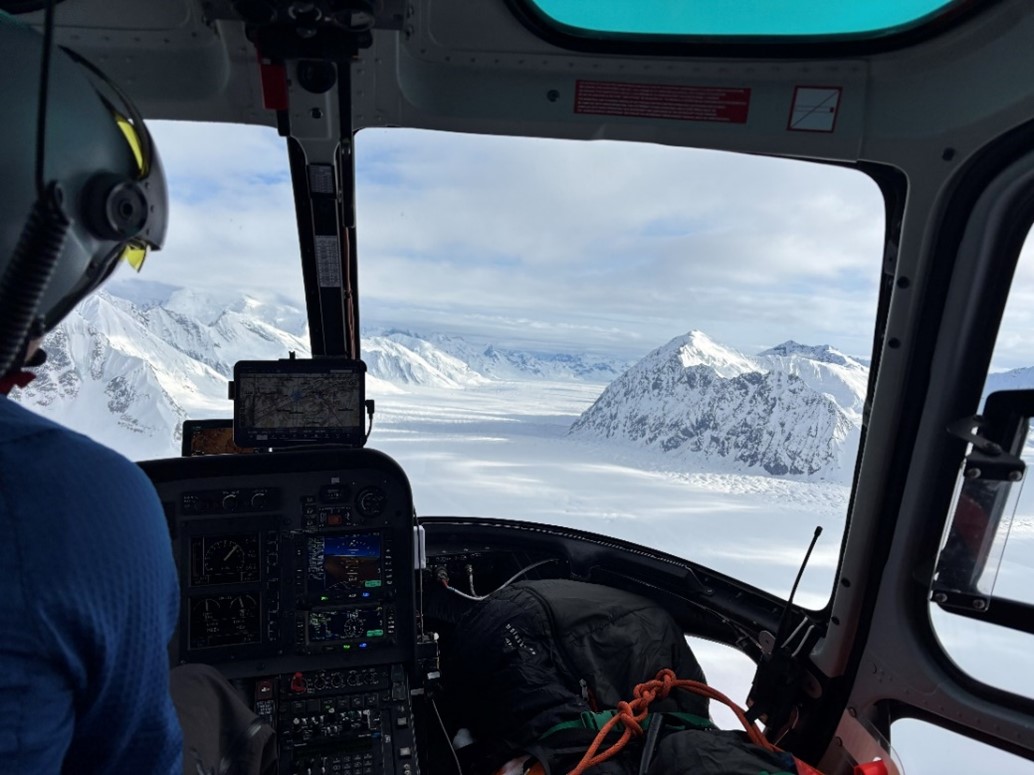 Views down the lower Kahiltna Glacier while en-route to Talkeetna. View of a snow covered glacier from the window a helicopter
