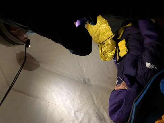 A ranger provides medical care to a prone patient in a tent