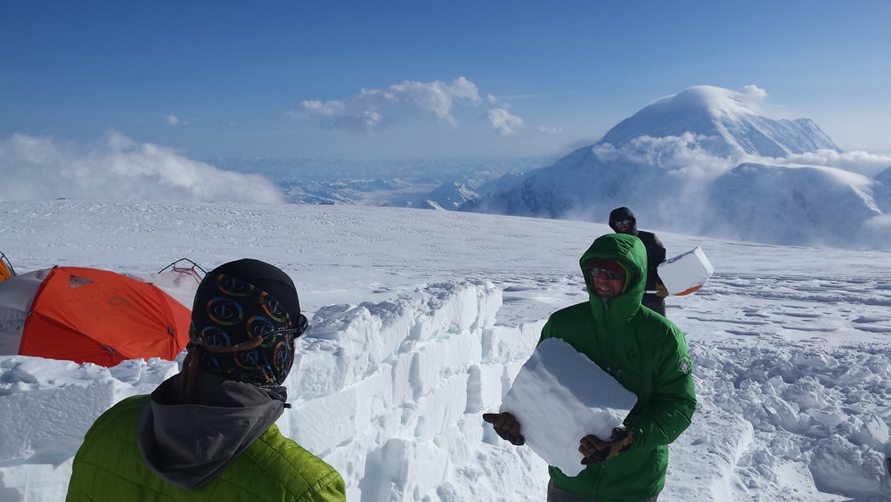Climbers building ice walls to protect tents from wind